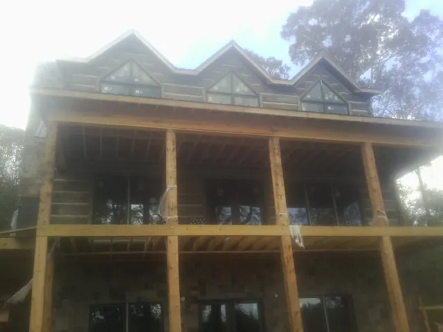Dormers and porch framing on a large log home under construction — Roof Coating work by our crew in Tyrone