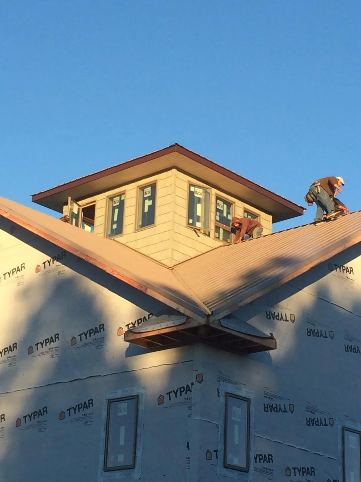 Roofers working around a rooftop cupola on a new metal roof at sunset — Roof Waterproofing in Tyrone by Roofing Brothers